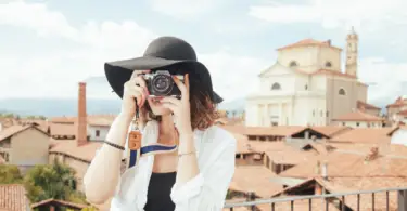 Stock photo of a woman taking a picture with a camera in front of a European city by the sea.