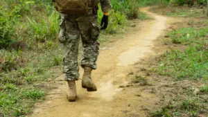Stock photo of a person in camo walking down a dirt path.