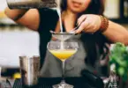 Stock photo of a bartender straining a drink into a glass.
