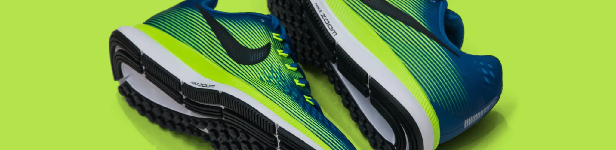Nike basketball shoes in lime green and blue, lying on a lime-green background.