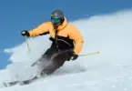 Action shot of skiier in yellow jacket skiing down a slope.
