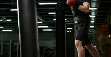 Man in black with black boxing shoes training on heavy bag