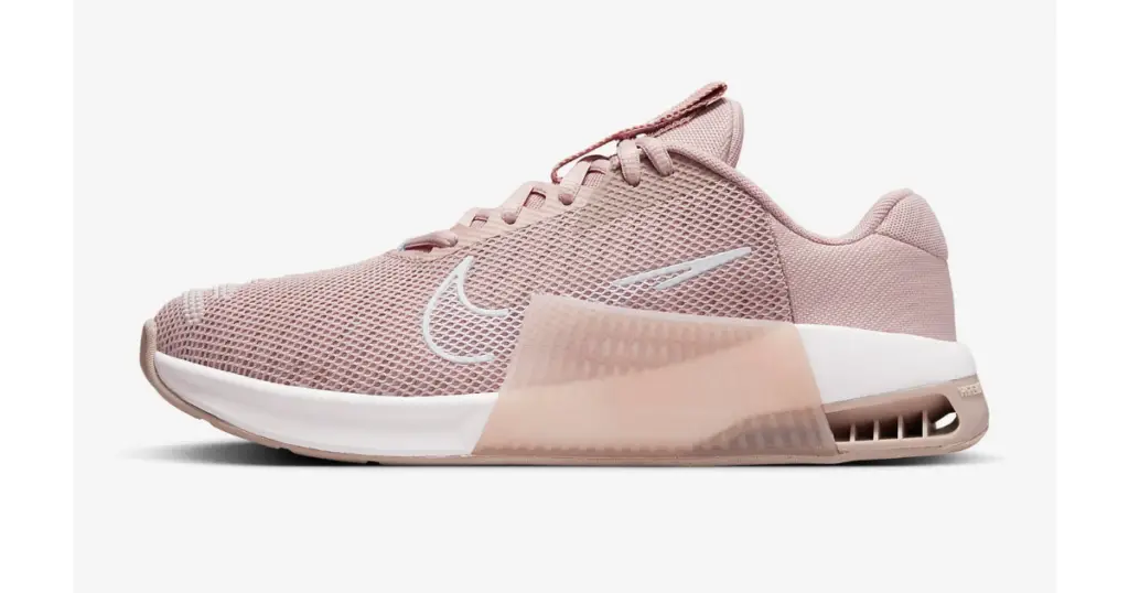 Product photo of Nike Metcon 6, light pale pink with white outsole and white outline of Nike logo on the side.