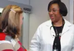 Stock photo of a Black, female doctor smiling at a patient.
