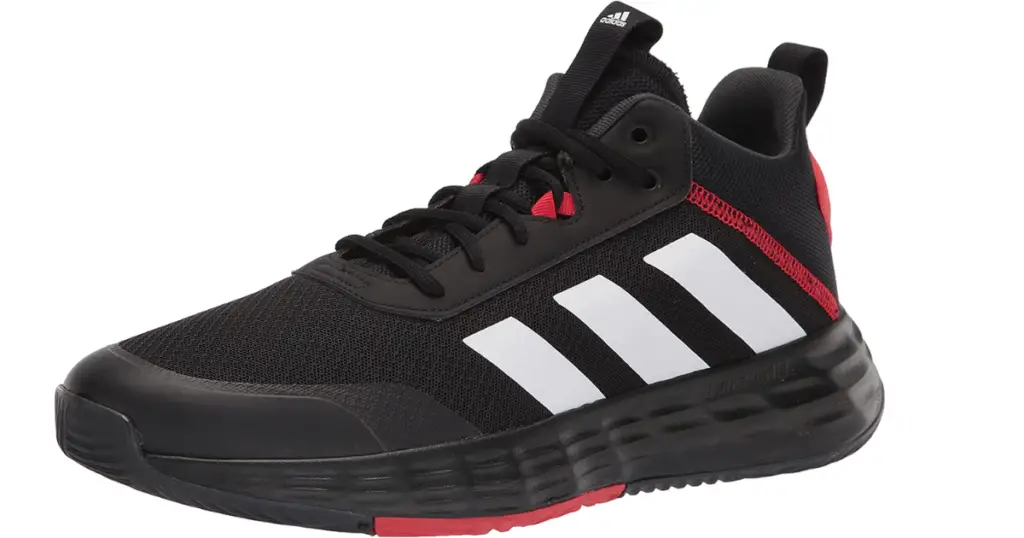 Photo of a black shoe with minimal red details and white Adidas stripes on the side.