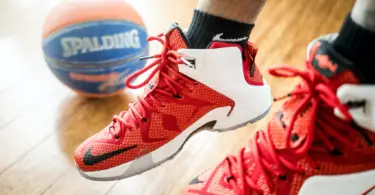 Image of red basketball shoes for flat feet in a sunlight gym, closeup, with a Spalding basketball in the background.